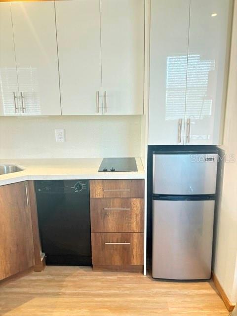 A kitchen features white upper cabinets, wood-toned lower cabinets, a black dishwasher, and a small refrigerator — 101 PALM HARBOR PARKWAY UNIT B225, PALM COAST, FL