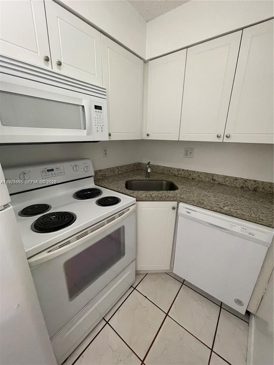 A small kitchen features white cabinets, a white electric stove, a dishwasher, and granite countertops — 5199 NW 7th St # 112, Miami FL 33126, MIAMI, FL