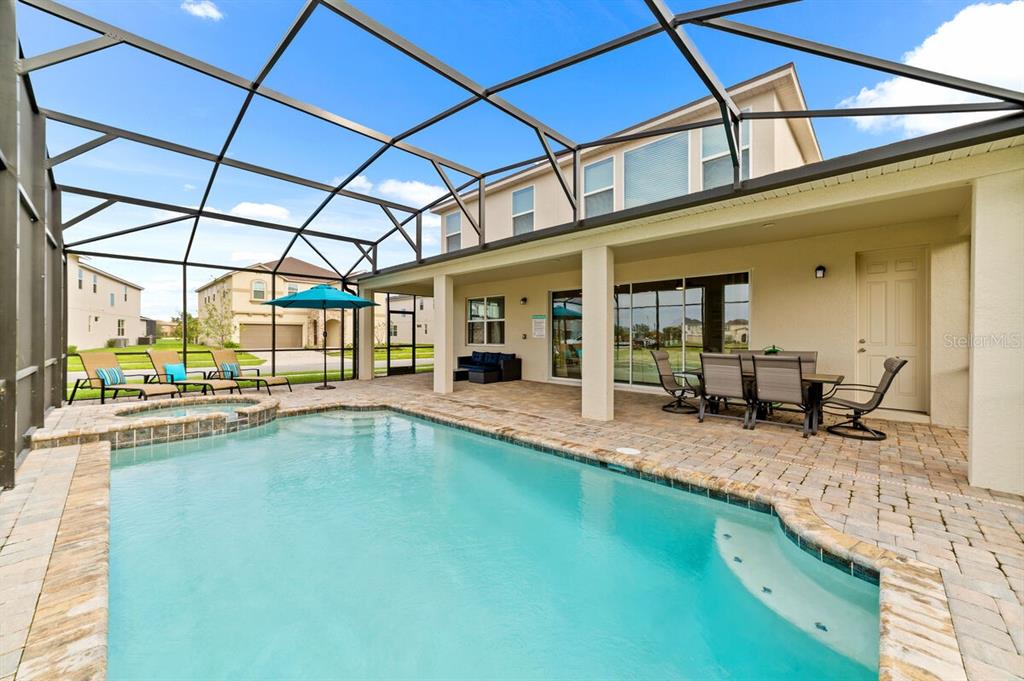 A screened-in patio features a swimming pool, hot tub, and outdoor dining area — 8951 HILTON RIDGE AVENUE, KISSIMMEE, FL