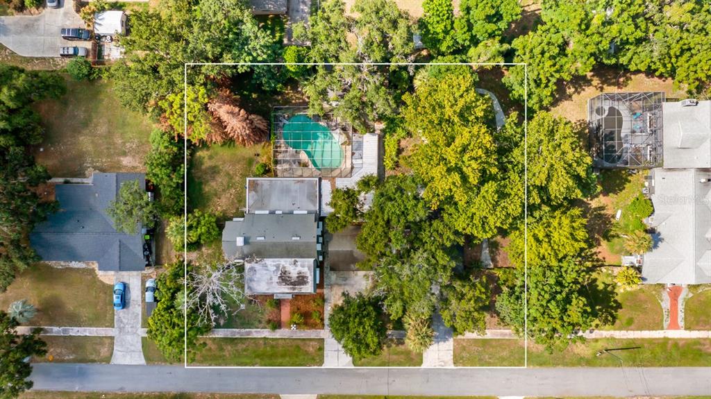 An aerial view shows a house with a pool and large trees on a lot — 127 E LAUREL AVENUE, HOWEY IN THE HILLS, FL