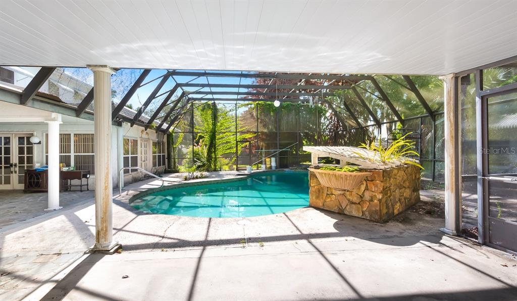 A screened-in patio features a swimming pool and a stone-clad planter box — 127 E LAUREL AVENUE, HOWEY IN THE HILLS, FL