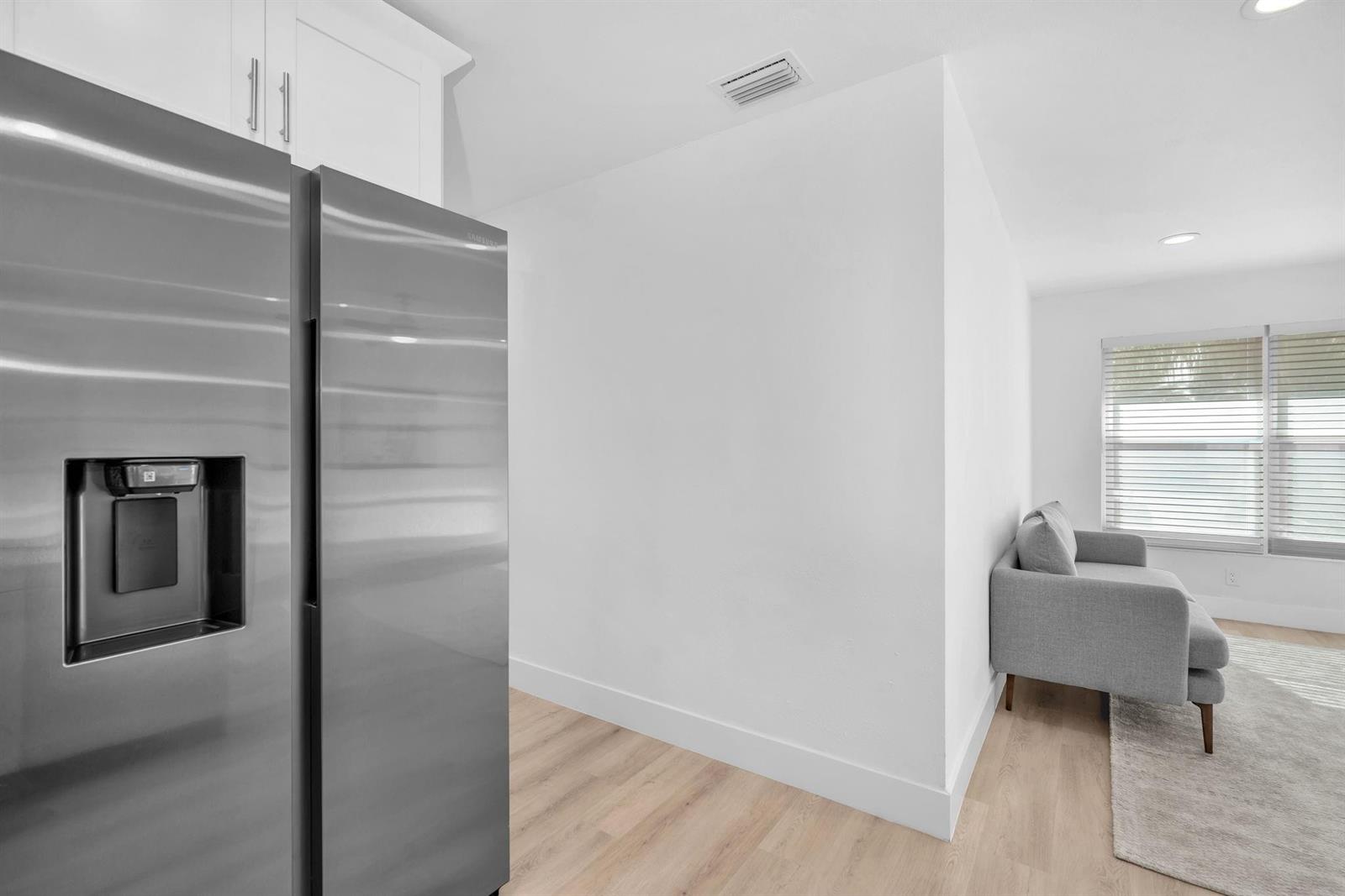 A stainless steel refrigerator stands next to a white wall in a modern kitchen area — 3308 E El Vedado Court, West Palm Beach FL 33405, WEST PALM BEACH, FL
