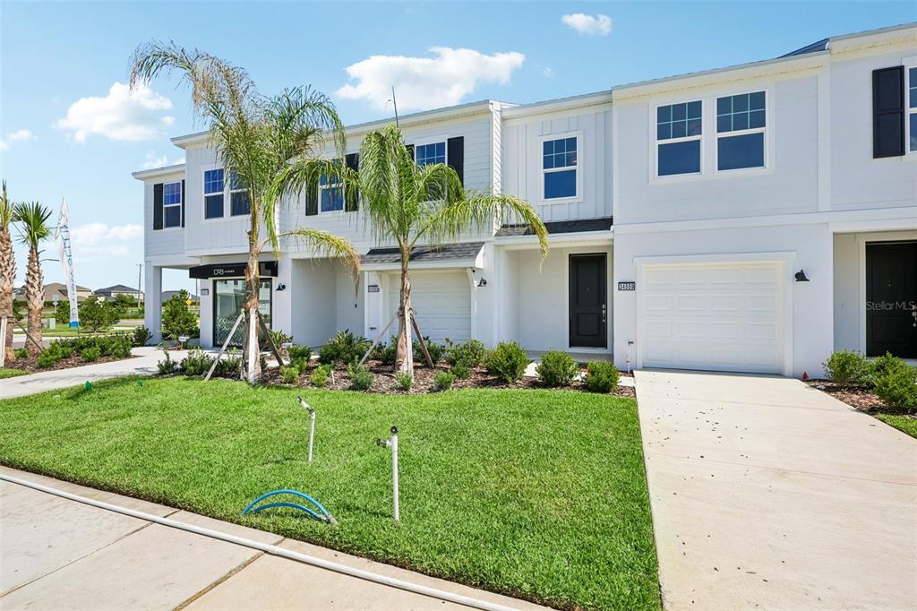 A two-story white townhouse with a garage, a small front lawn, and two palm trees — 34559 TURPINS AVENUE, ZEPHYRHILLS, FL