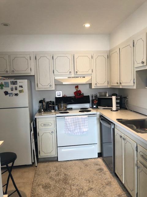 A kitchen features white cabinets, a white stove, a refrigerator, and a beige area rug — 370 Saxony Trail, Delray Beach FL 33446, DELRAY BEACH, FL