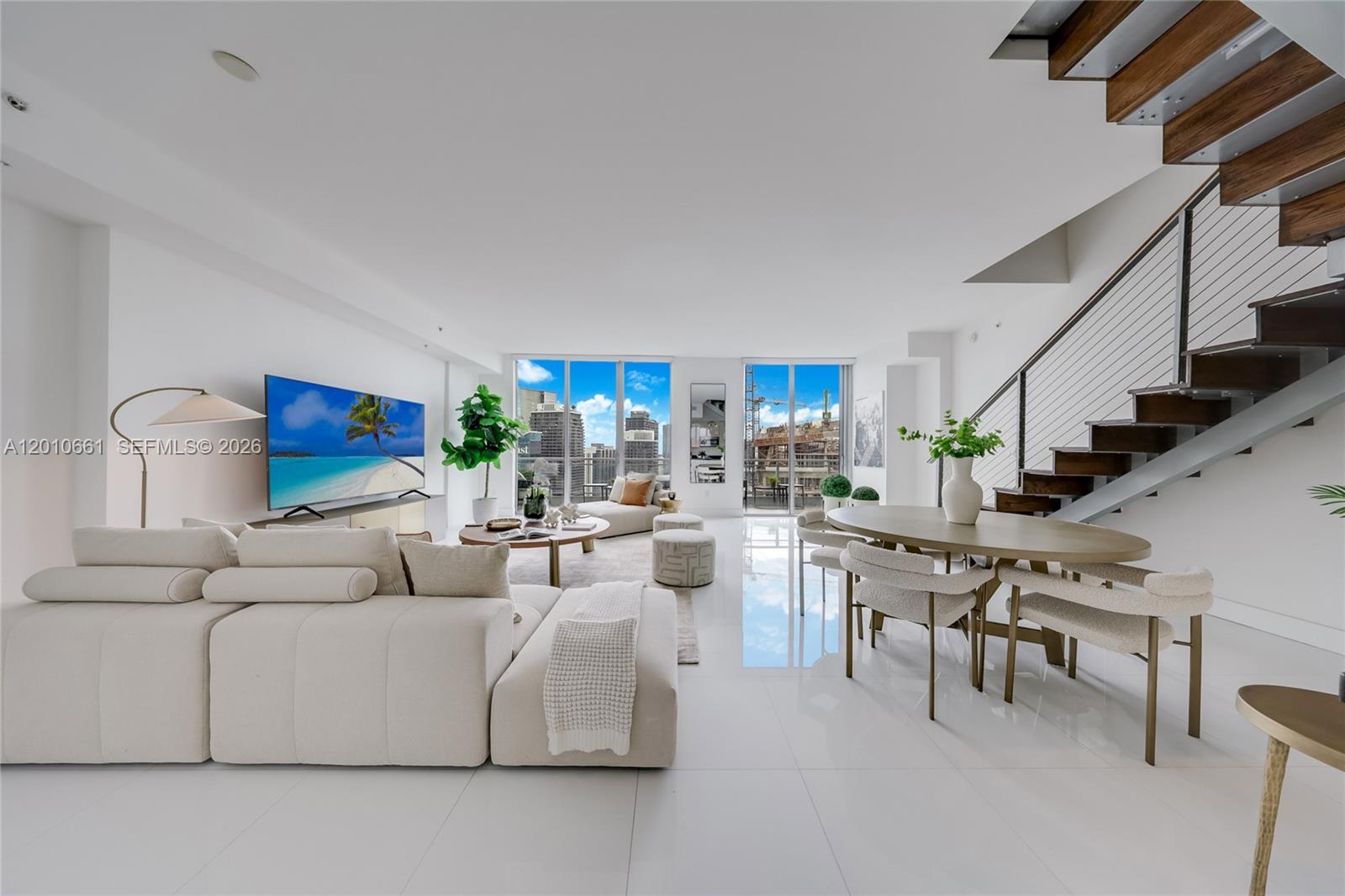 A modern living and dining area features white tile floors, a staircase, and floor-to-ceiling windows — 92 SW 3rd St # 5202, Miami FL 33130, MIAMI, FL
