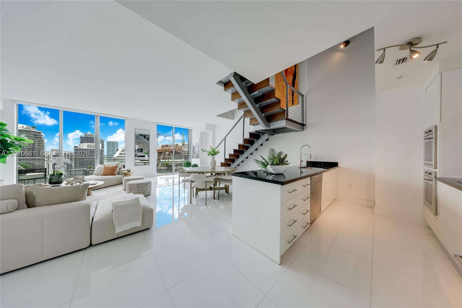 A modern open-concept living area features white tile floors, a staircase, and floor-to-ceiling windows — 92 SW 3rd St # 5202, Miami FL 33130, MIAMI, FL