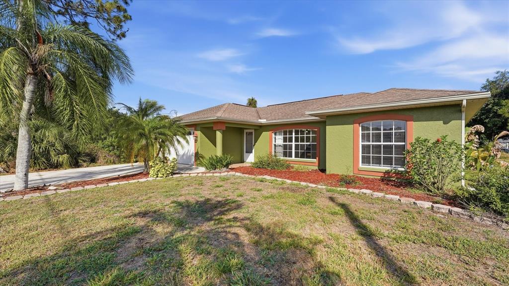 A single-story house with green stucco walls, orange trim, and a brown shingled roof — 3196 CIRCLEVILLE STREET, NORTH PORT, FL