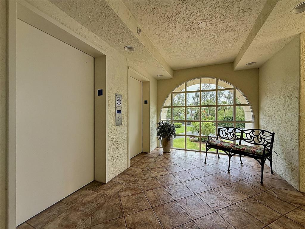 An elevator lobby features tiled floors, a wrought iron bench, and an arched window — 4801 OSPREY DRIVE S UNIT 103, ST PETERSBURG, FL