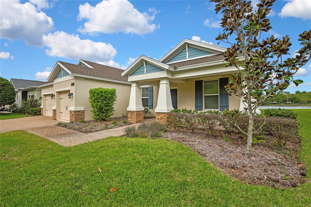 A single-story suburban house with a tan stucco exterior, stone accents, and a paved driveway — 19863 TATTNALL WAY, BROOKSVILLE, FL