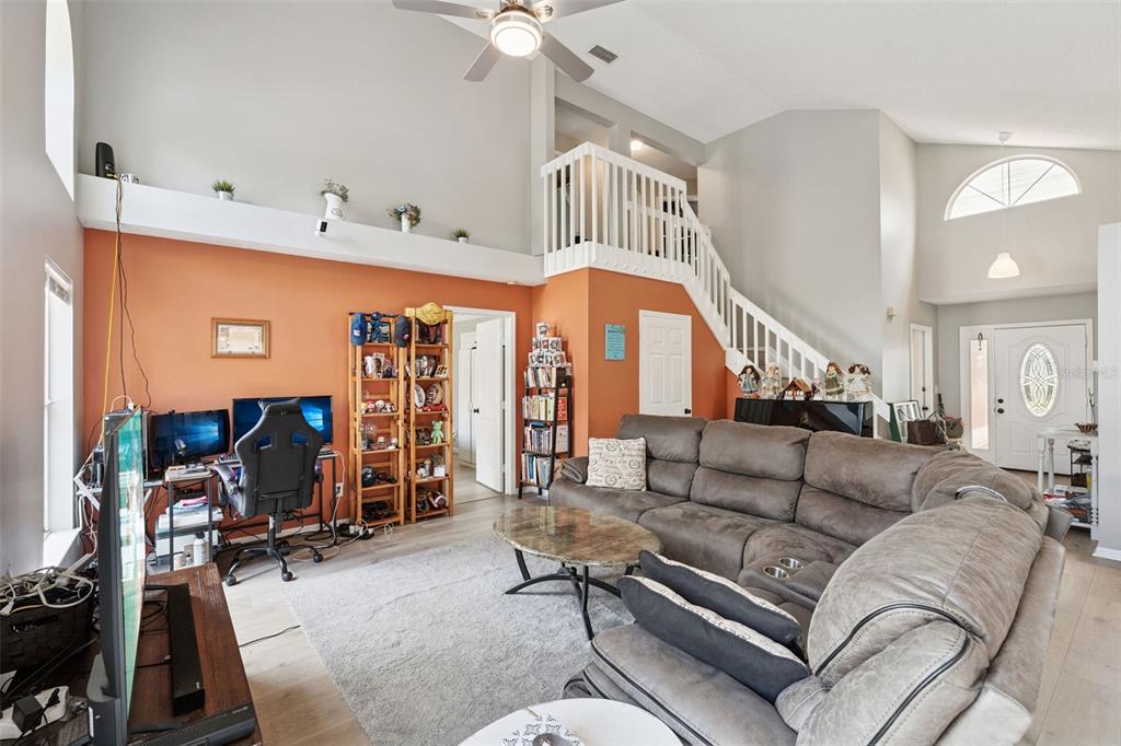A living room features a vaulted ceiling, a staircase, a sectional sofa, and a desk area — 4485 WEEPING WILLOW CIRCLE, CASSELBERRY, FL