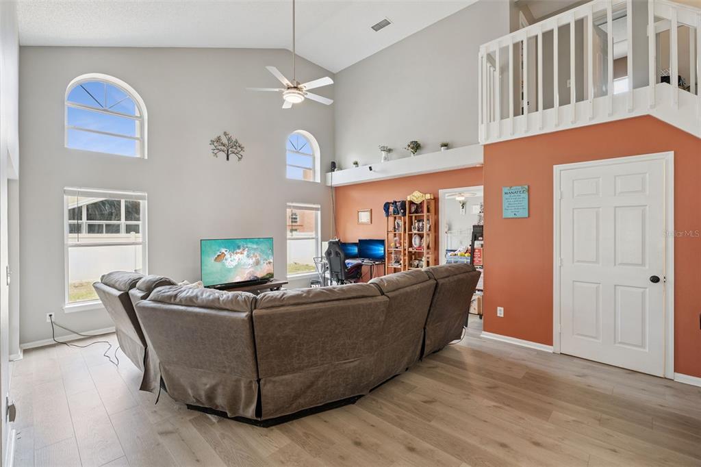 A living room features vaulted ceilings, light wood flooring, a large sectional sofa, and a loft — 4485 WEEPING WILLOW CIRCLE, CASSELBERRY, FL