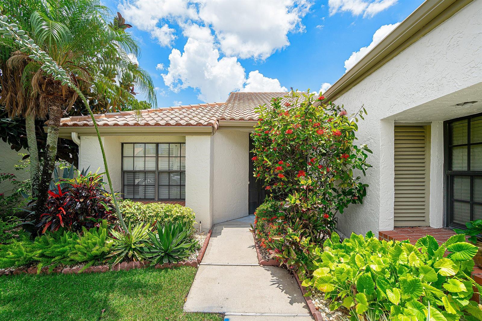A concrete walkway leads to the front entrance of a house with a tiled roof — 5635 Kiowa Circle, Boynton Beach FL 33437, BOYNTON BEACH, FL