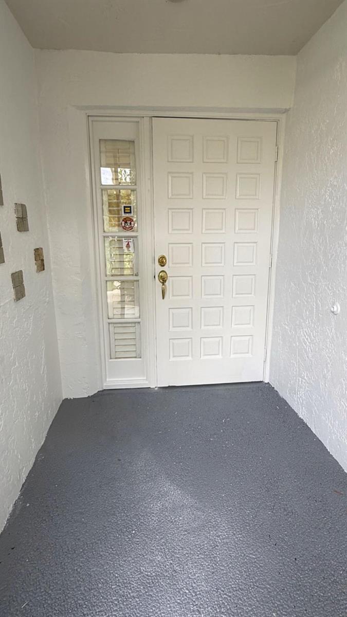 A white front door with a side window panel sits on a gray concrete porch — 5635 Kiowa Circle, Boynton Beach FL 33437, BOYNTON BEACH, FL
