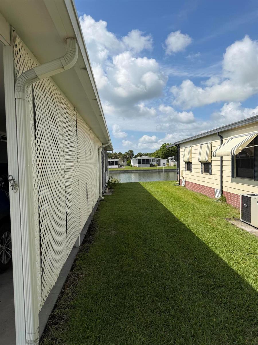 A grassy side yard between two mobile homes leads toward a canal under a blue sky — 1520 SW 35th Circle, Okeechobee FL 34974, OKEECHOBEE, FL
