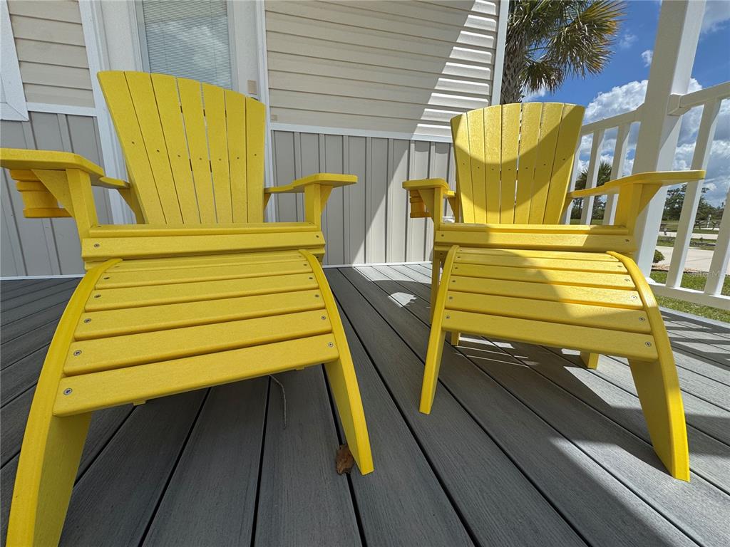 Two bright yellow Adirondack chairs with matching ottomans sit on a gray composite deck — 16950 HIGHWAY 630E UNIT 140, LAKE WALES, FL