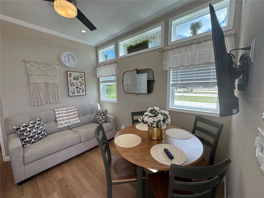A small living and dining area features a gray sofa, round wooden table, and windows — 16950 HIGHWAY 630E UNIT 140, LAKE WALES, FL