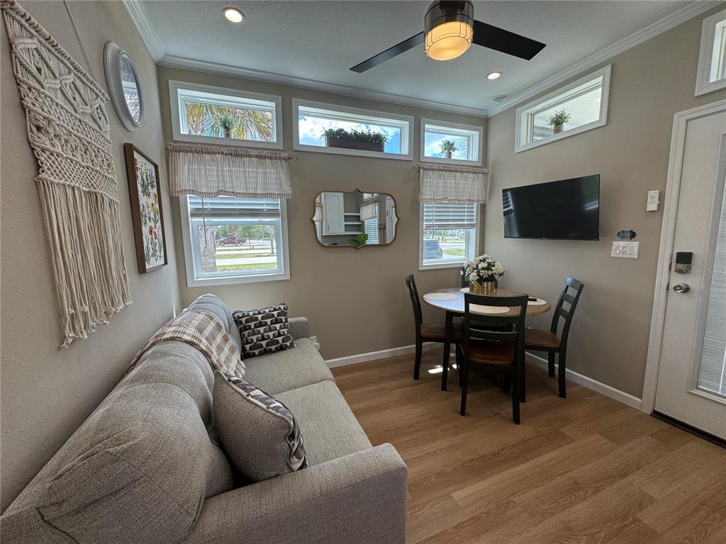 A living room features a sofa, a small dining table, and a wall-mounted television — 16950 HIGHWAY 630E UNIT 140, LAKE WALES, FL