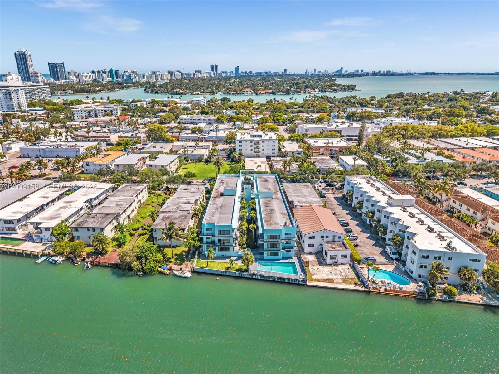 An aerial view shows waterfront apartment buildings with swimming pools and surrounding residential neighborhoods — 1165 Marseille Dr # 9, Miami Beach FL 33141, MIAMI BEACH, FL