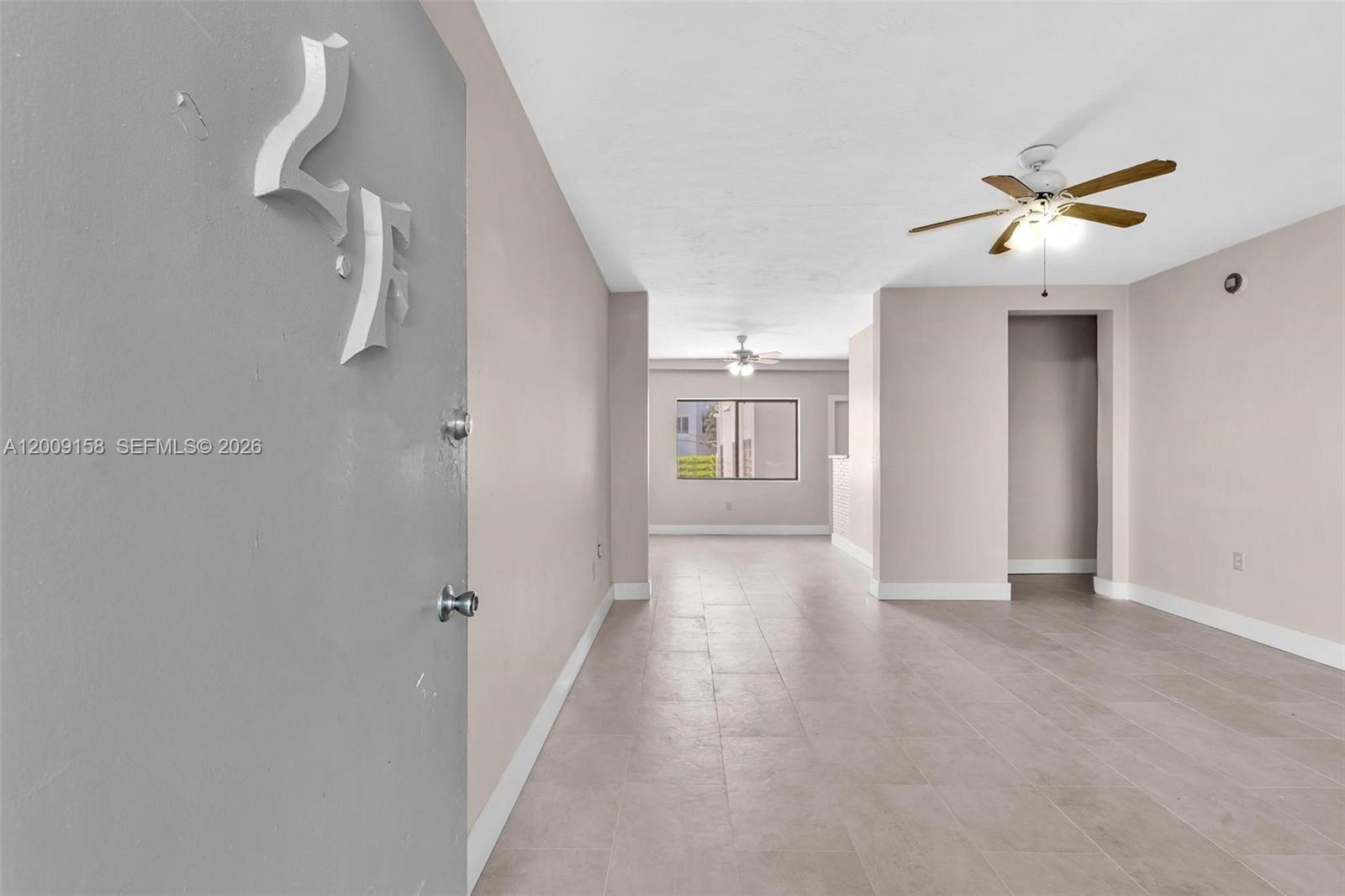 An interior view shows a tiled living area with light walls and two ceiling fans — 1165 Marseille Dr # 9, Miami Beach FL 33141, MIAMI BEACH, FL