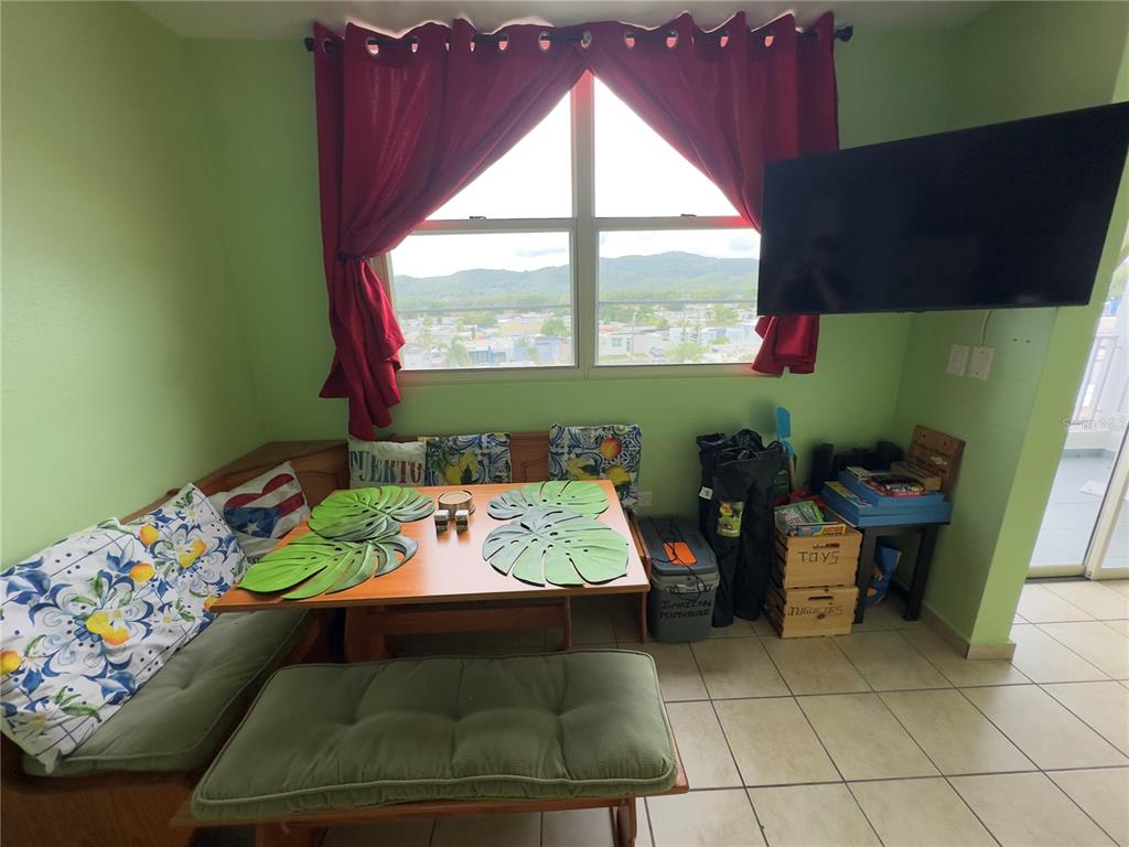 A dining area features a corner bench, a wooden table, and a view of mountains — 500 CALLE SAN PATRICIO Apt D 402, FAJARDO, PR