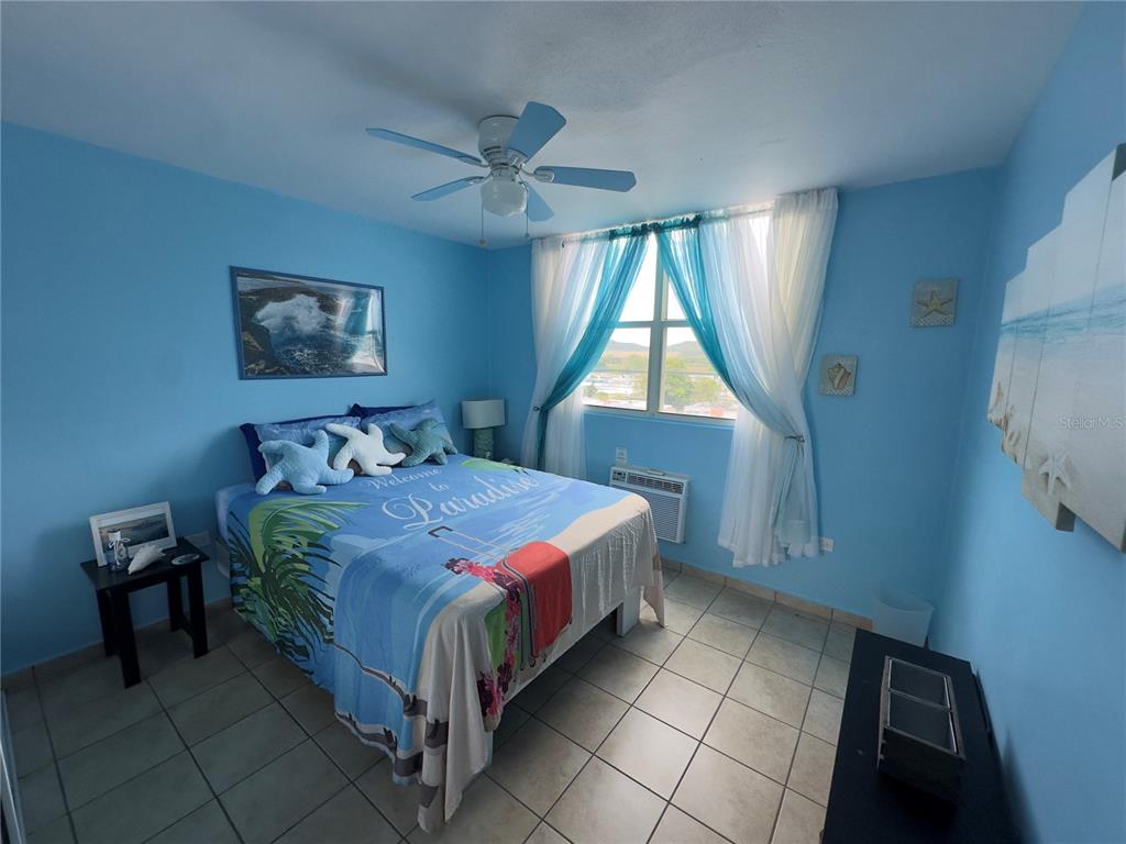 A bedroom with blue walls, tile flooring, a ceiling fan, and a beach-themed bedspread — 500 CALLE SAN PATRICIO Apt D 402, FAJARDO, PR