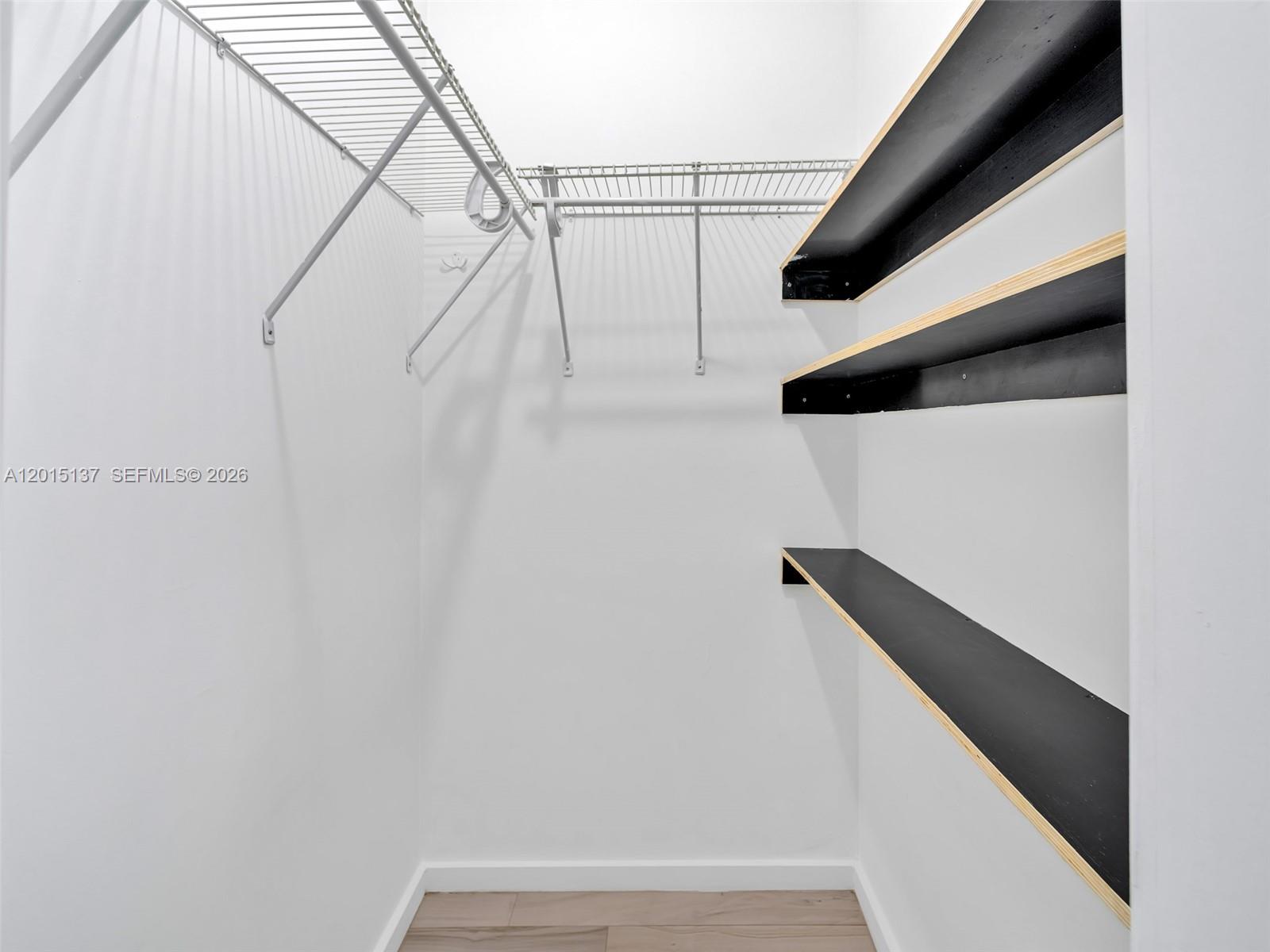 A walk-in closet features white walls, wire shelving, and three black wooden shelves — 820 15th St # 202, Miami Beach FL 33139, MIAMI BEACH, FL