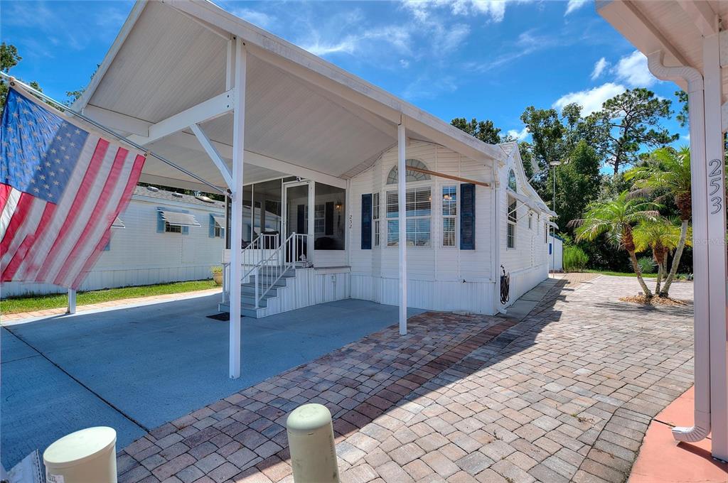 A white mobile home features a covered carport, a screened porch, and a brick paver driveway — 252 CITRUS RIDGE DRIVE, DAVENPORT, FL