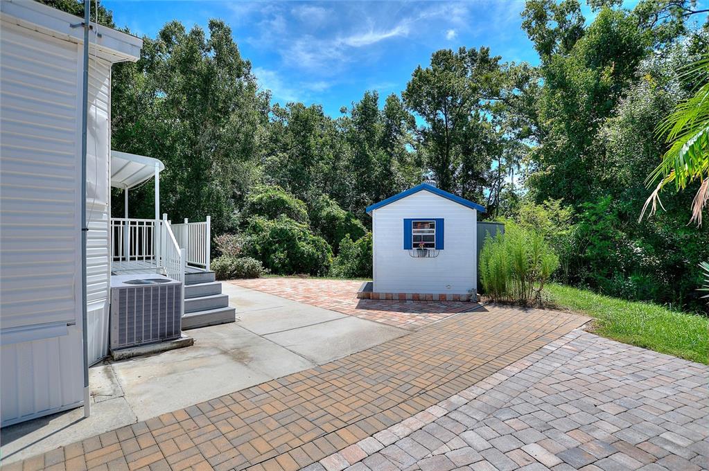 A white shed sits on a paved patio next to a mobile home with stairs — 252 CITRUS RIDGE DRIVE, DAVENPORT, FL