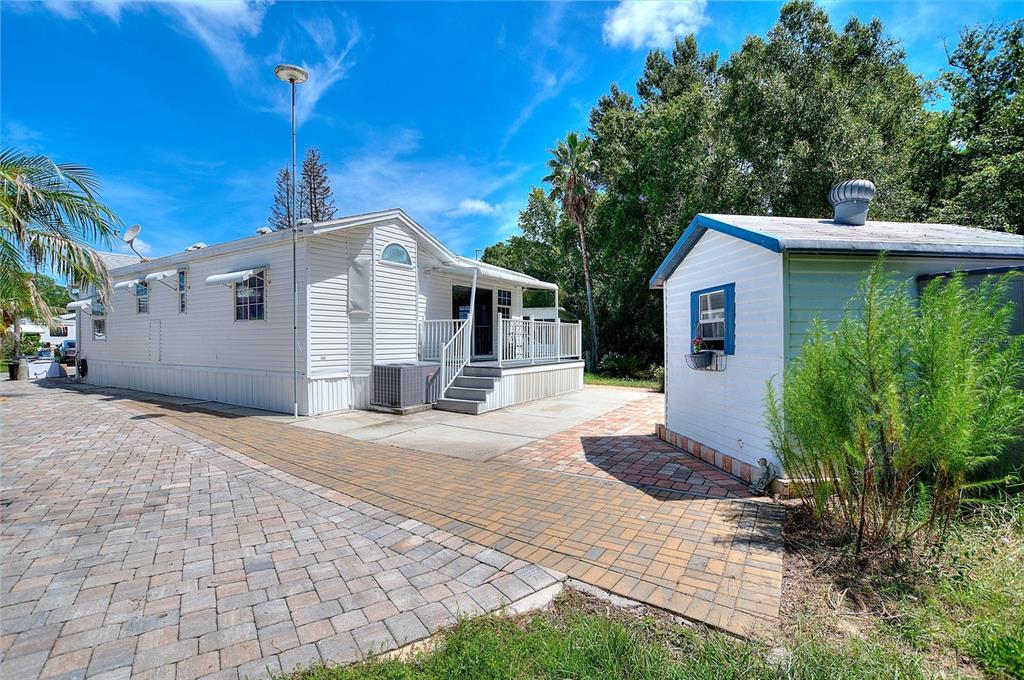 A white mobile home with a paved driveway and a small detached shed nearby — 252 CITRUS RIDGE DRIVE, DAVENPORT, FL
