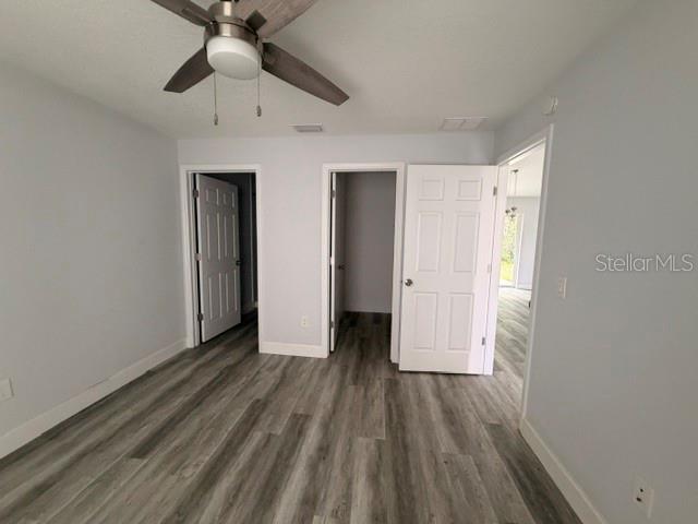 A bedroom with light gray walls, wood-look flooring, a ceiling fan, and two open doorways — 3226 SW 152ND COURT, OCALA, FL