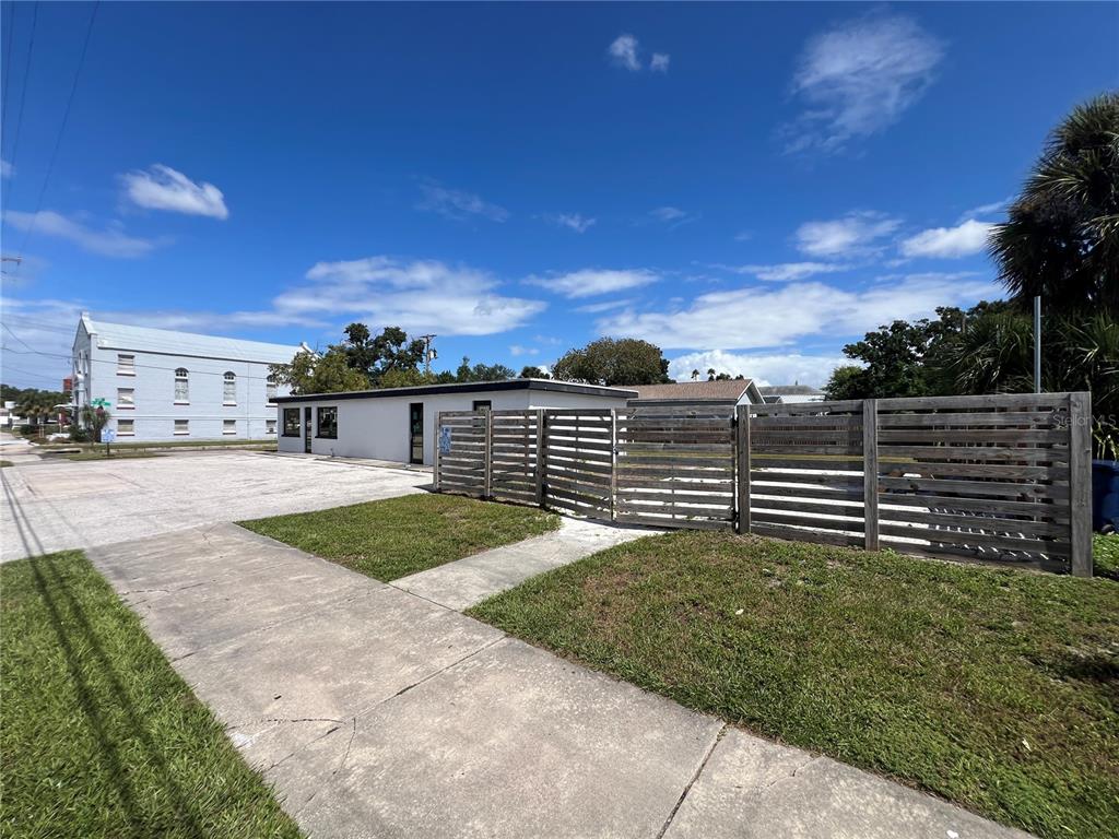 A white commercial building sits next to a wooden fence and a paved parking lot — 1713 N ALBANY AVENUE, TAMPA, FL