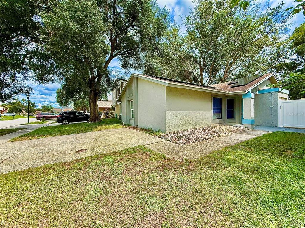A single-story house exterior with a concrete driveway, rock landscaping, and solar panels on roof — 10309 PARKCREST DRIVE, TAMPA, FL
