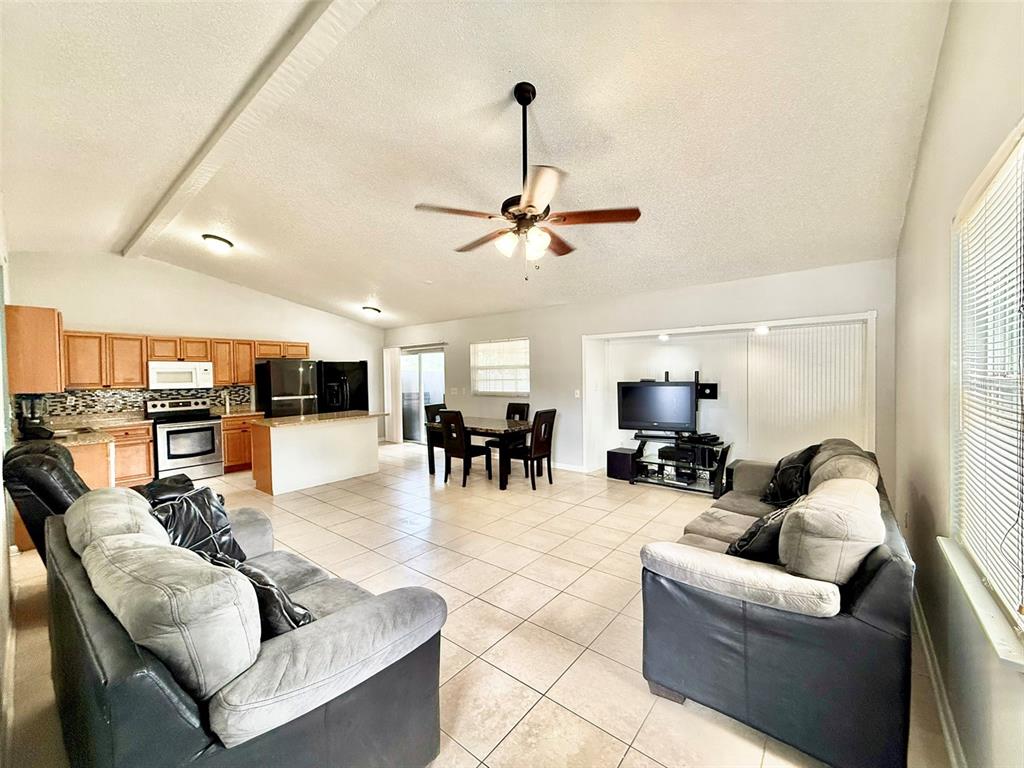 An open-concept living room and kitchen with tile flooring, a ceiling fan, and neutral walls — 10309 PARKCREST DRIVE, TAMPA, FL