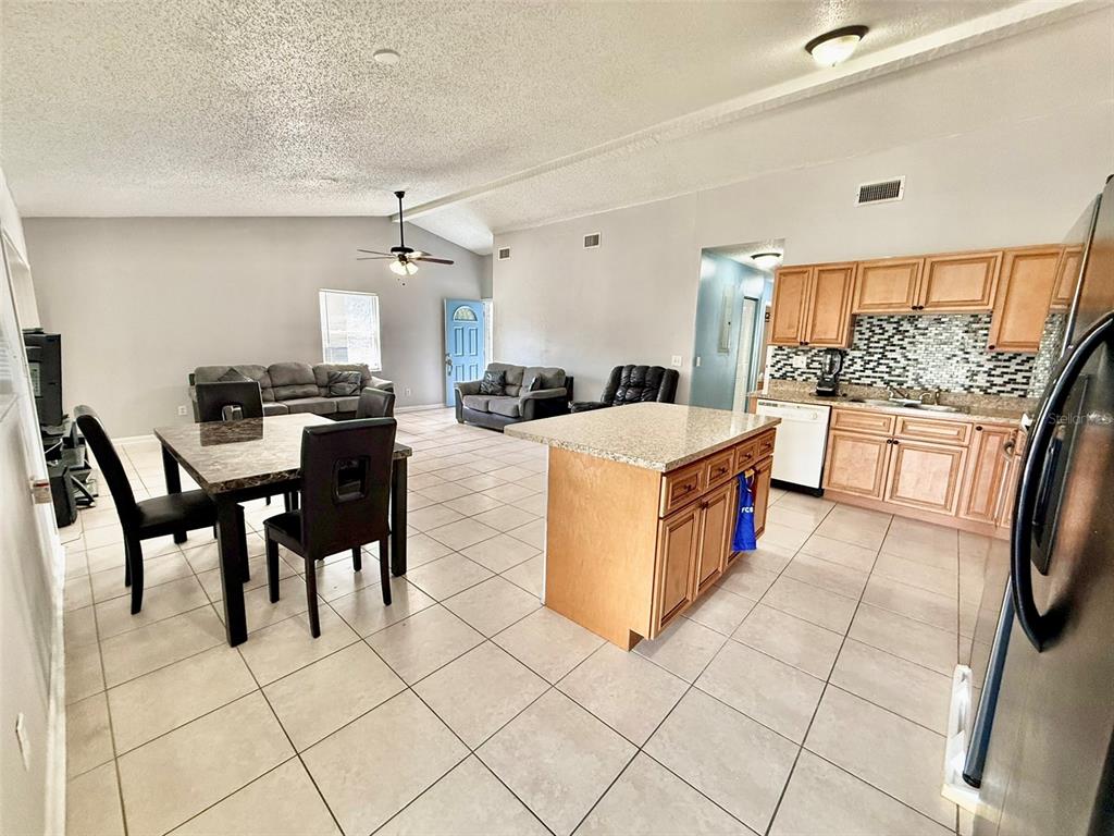 An open-concept living and dining area features tile flooring, a kitchen island, and wood cabinets — 10309 PARKCREST DRIVE, TAMPA, FL