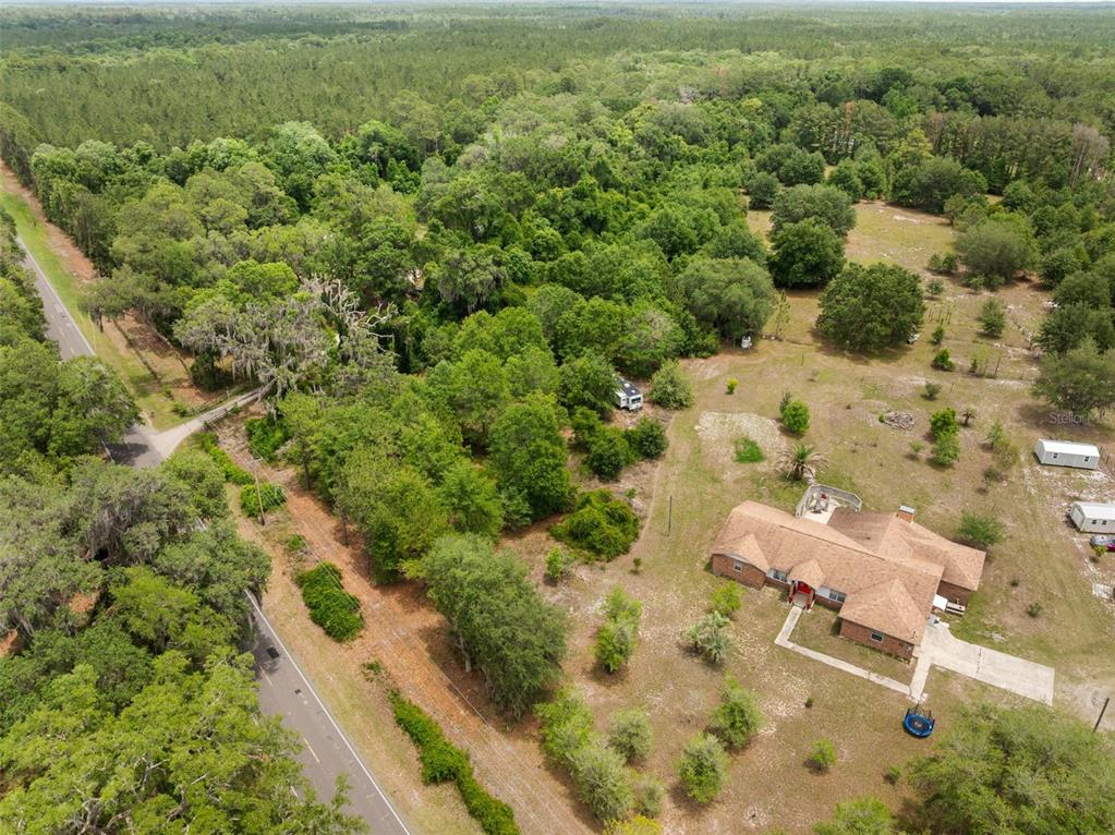 An aerial view shows a brick house on a large, wooded lot near a road — 2919 SE COUNTY ROAD 234, GAINESVILLE, FL