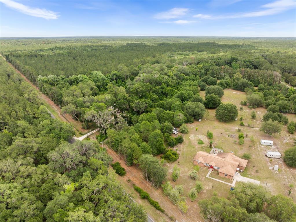 An aerial view shows a house with a brown roof surrounded by trees and fields — 2919 SE COUNTY ROAD 234, GAINESVILLE, FL