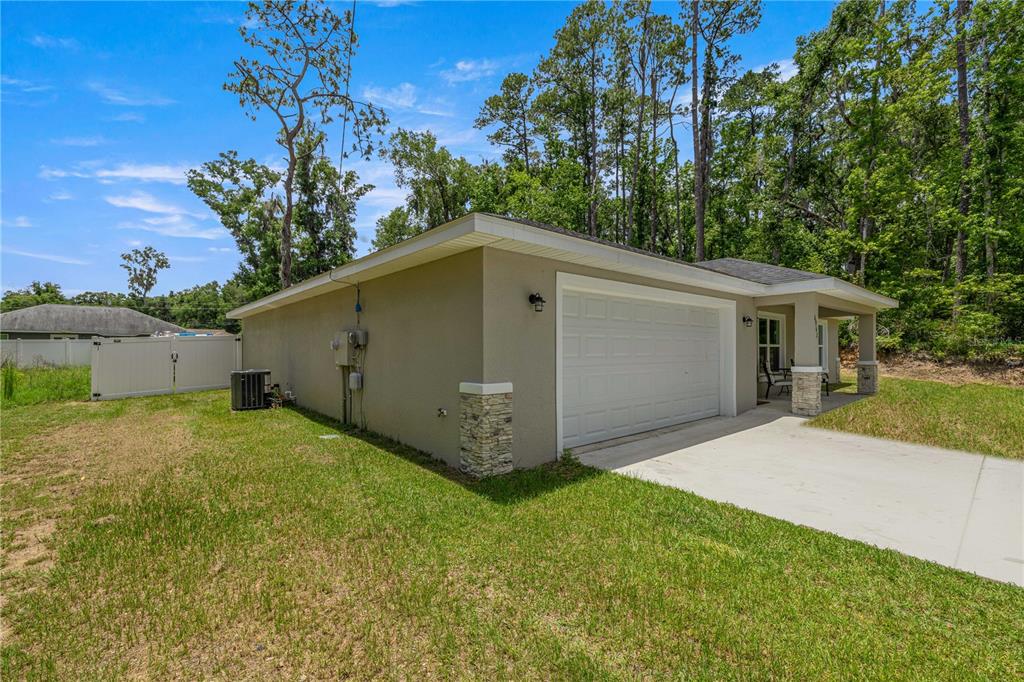 A side view of a house exterior featuring a garage, stone accents, and a driveway — 6962 SE 124TH STREET, BELLEVIEW, FL