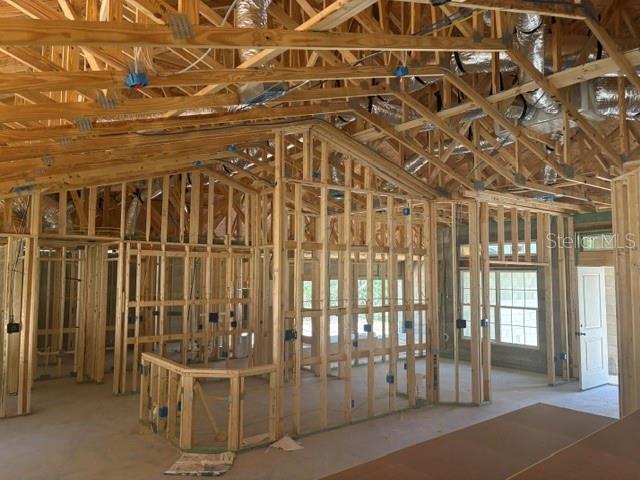 The interior of a house under construction shows exposed wooden framing, roof trusses, and ductwork — 12188 SW 81ST STREET, DUNNELLON, FL