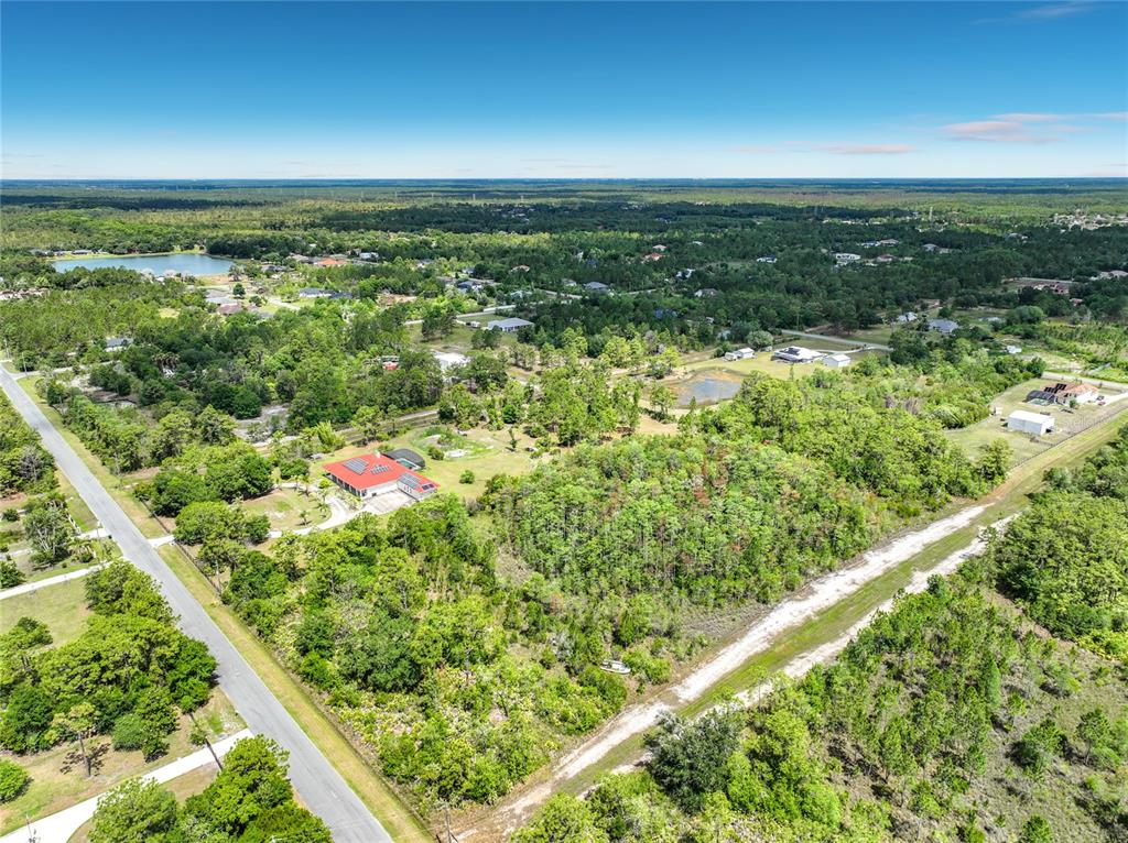An aerial view shows a house with a red roof surrounded by trees and land — 00 PADDOCK STREET, ORLANDO, FL