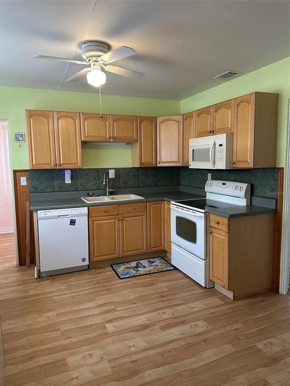A kitchen features light wood cabinets, green walls, a white stove, and a white dishwasher — 4142 6TH AVENUE N, ST PETERSBURG, FL