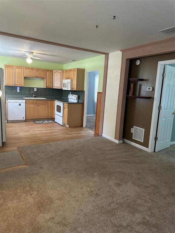 A kitchen with light wood cabinets and a white dishwasher opens to a carpeted room — 4142 6TH AVENUE N, ST PETERSBURG, FL