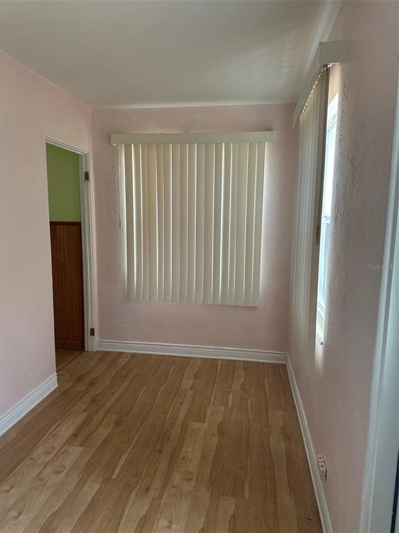A room with light pink walls, wood-look flooring, and vertical blinds on the windows — 4142 6TH AVENUE N, ST PETERSBURG, FL