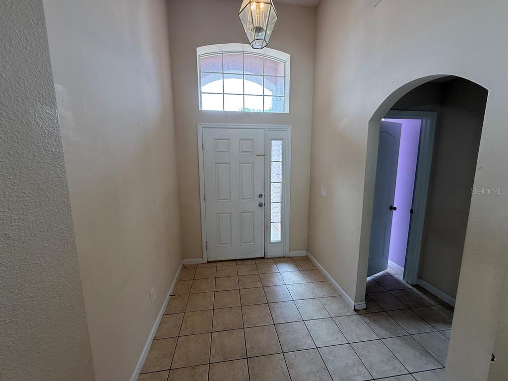 An entryway features a white front door, a transom window, and beige tile flooring — 3045 MERLOT WAY, CLERMONT, FL