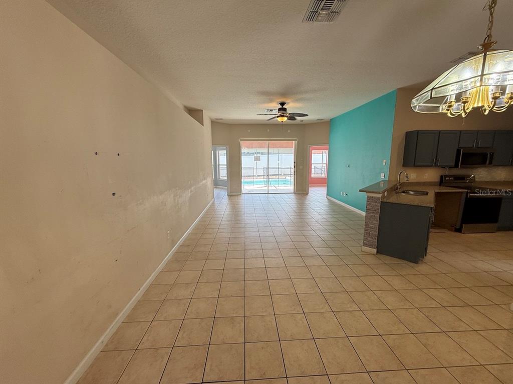 An open-concept living area with tile floors, a kitchen, and a view of a pool — 3045 MERLOT WAY, CLERMONT, FL