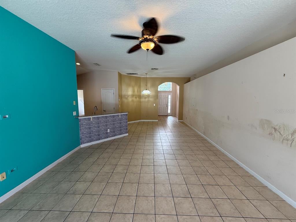 A living area features tiled floors, a teal accent wall, and a kitchen breakfast bar — 3045 MERLOT WAY, CLERMONT, FL