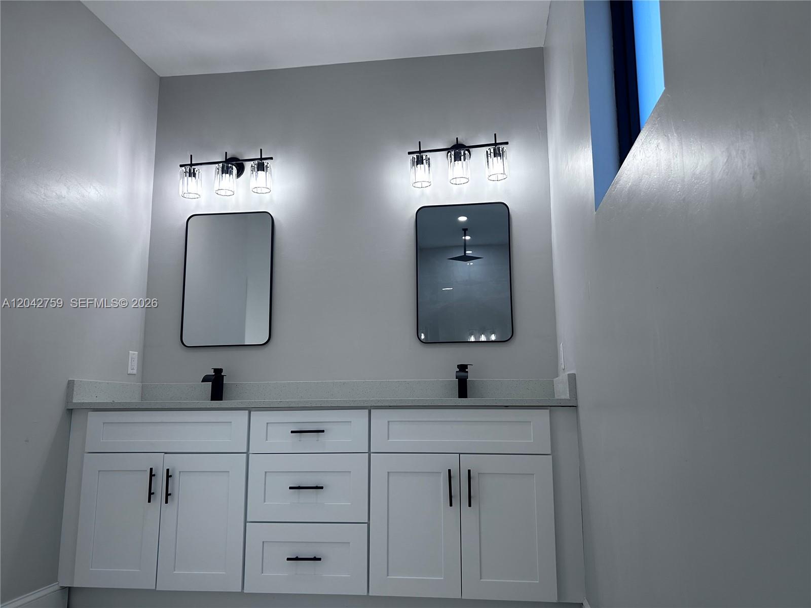 A bathroom features a double vanity with white cabinets, black hardware, and two wall mirrors — 1126 Milwaukee Blvd, Lehigh Acres FL 33974, LEHIGH ACRES, FL