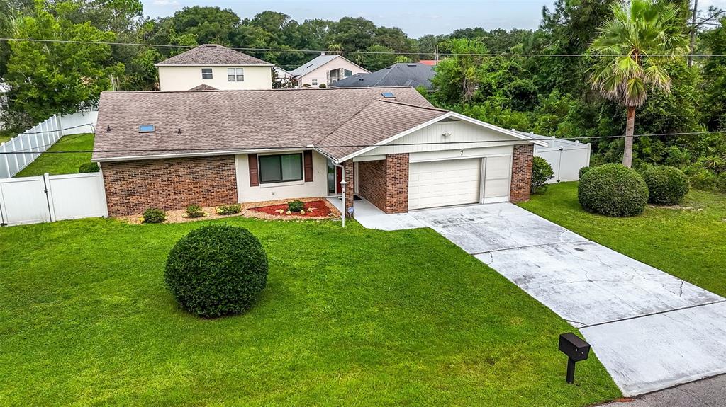 A single-story brick and siding house with a garage, driveway, and manicured lawn — 7 PERKINS LANE, PALM COAST, FL