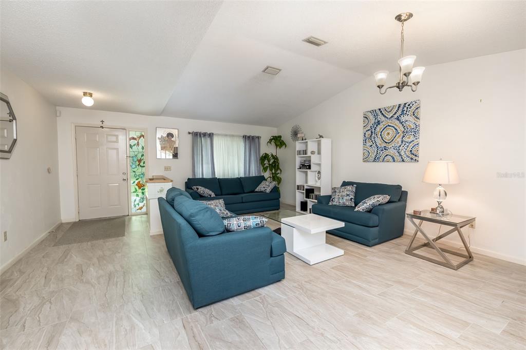 A living room features blue sofas, a white coffee table, and light-colored tile flooring — 7 PERKINS LANE, PALM COAST, FL