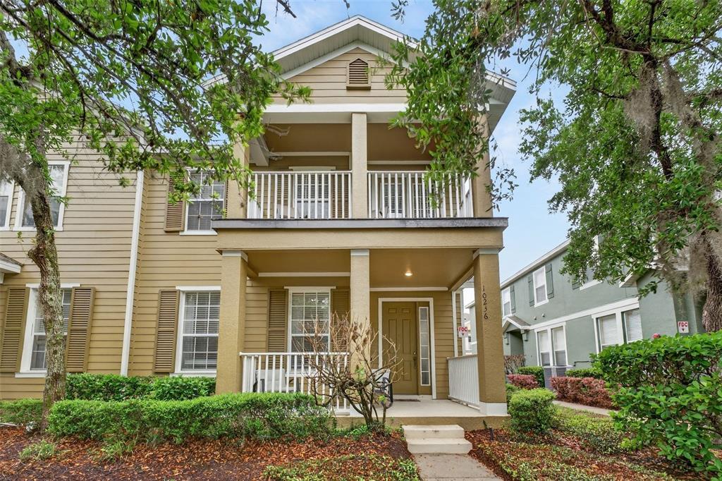A two-story tan house features a front porch, a second-story balcony, and brown shutters — 10236 LAKE DISTRICT LANE UNIT 35C, ORLANDO, FL
