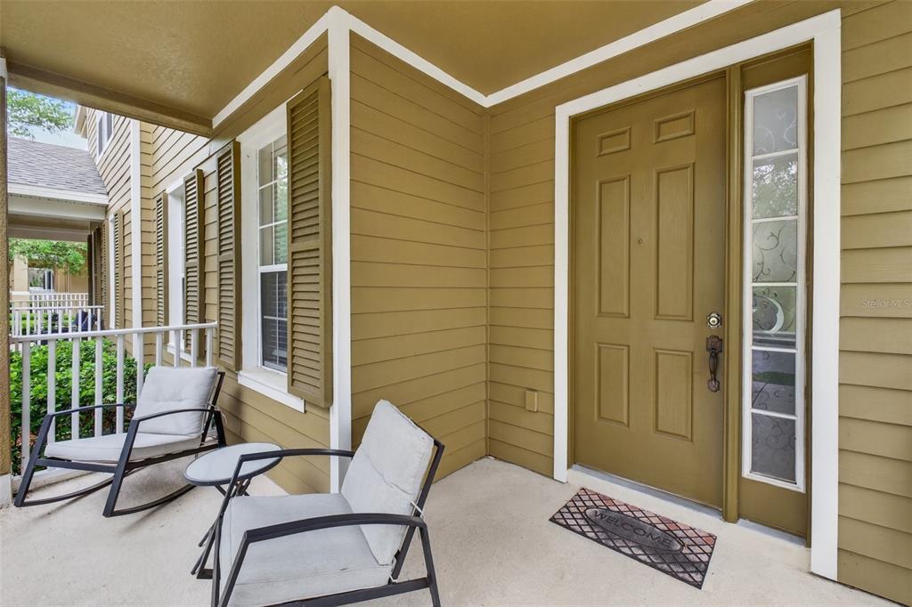 A covered porch with two chairs, a small table, and a brown front door — 10236 LAKE DISTRICT LANE UNIT 35C, ORLANDO, FL